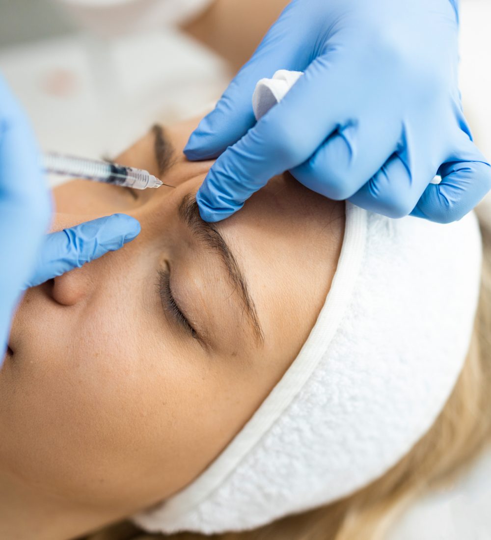 Beautician makes botox injections in the area between the eyebrows. Anti aging procedure